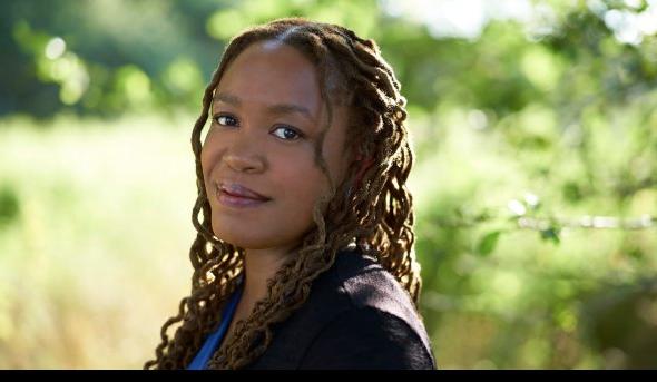 Headshot of woman wearing black blazer in front of nature background