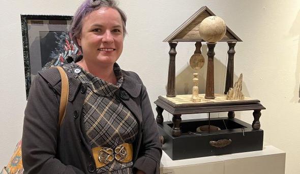 A woman poses with a piece of artwork. 