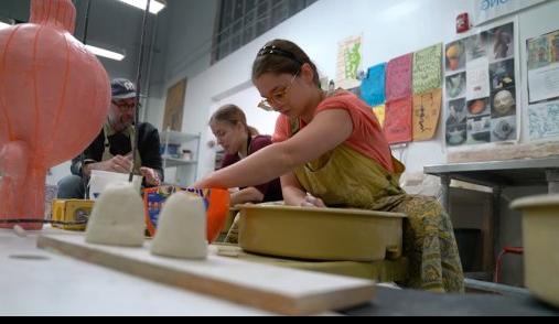 Student sculpts with clay in art studio.